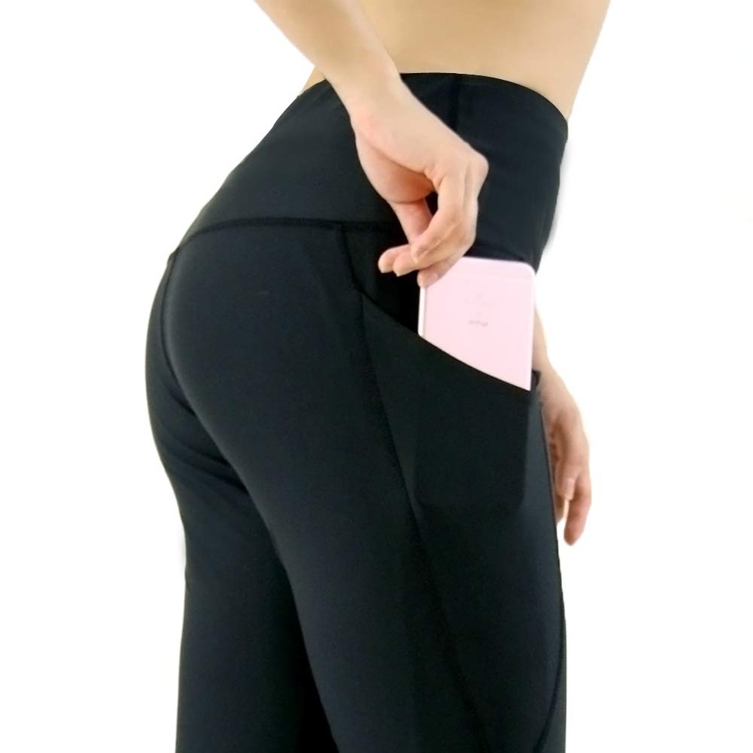 Närbild på en sidoficka på ett par svarta yogabyxor där en person placerar en mobiltelefon.